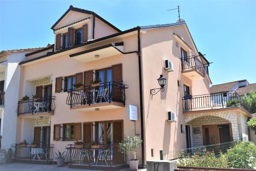 罗维尼Apartments & Rooms Ivana的一座大型粉红色建筑,设有阳台和桌子