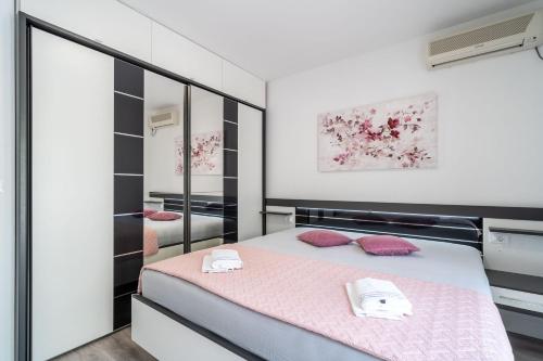 米利尼Deluxe apartment的一间卧室配有一张带粉红色床单和镜子的床