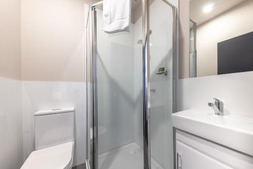 悉尼Lakemba Hotel的带淋浴和盥洗盆的白色浴室