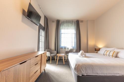 悉尼Lakemba Hotel的酒店客房设有一张大床和一台电视。
