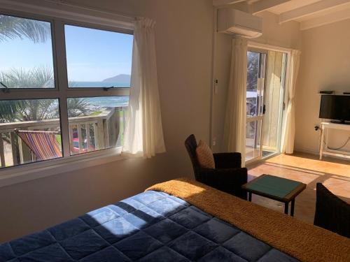 库珀海滩Driftwood Beachfront Accommodation, Cable Bay, Owhetu的一间卧室设有一张床和一个大窗户