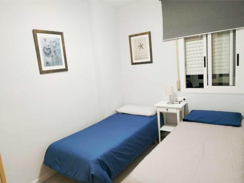 卡拉费尔APARTAMENTO EN EL CENTRO DE CALAFELL的一间卧室设有两张床、床头柜和窗户。