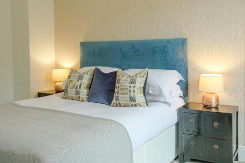 艾恩布里奇The Water Rat Ironbridge的一间卧室配有一张带蓝色床头板的床和两盏灯。