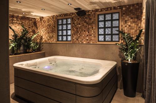 沙托纳Le Domaine des Prés Verts Suites & Chambres avec Jacuzzi Privatif à Châteauneuf的植物客房内的按摩浴缸