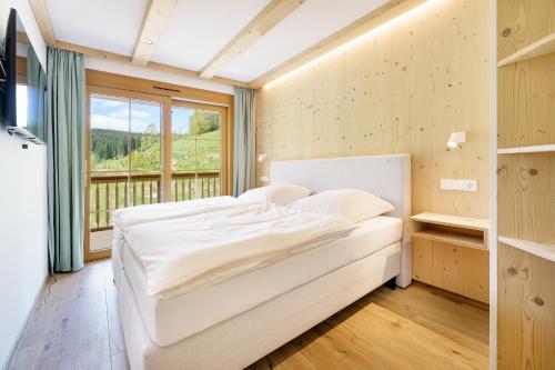 费尔德伯格SCHWARZENBACH - Apartments & Rooftop Pool的卧室配有白色的床和窗户。