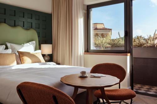 罗马The Hoxton, Rome的酒店客房设有床、桌子和窗户。