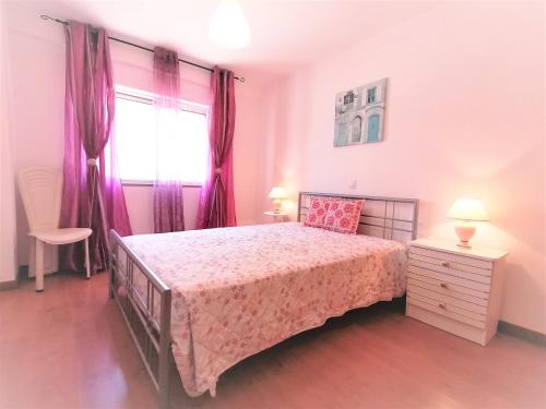 波尔蒂芒Encosta da Marina Beach Apartment的一间卧室配有一张床和一个带紫色窗帘的窗户