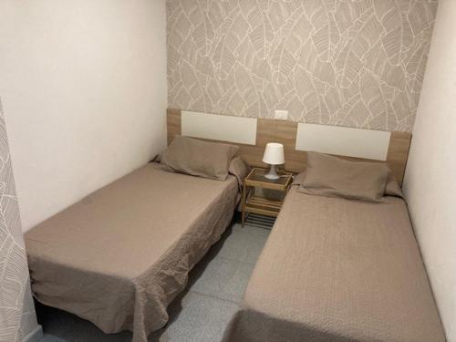 大加那利岛拉斯帕尔马斯Vacacional Playa Las Canteras的一张小房间内的两张床,配有一张桌子上的灯