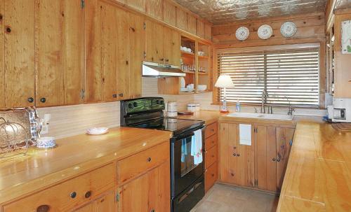 温伯利Deja View Cabin的厨房配有木制橱柜和炉灶烤箱。