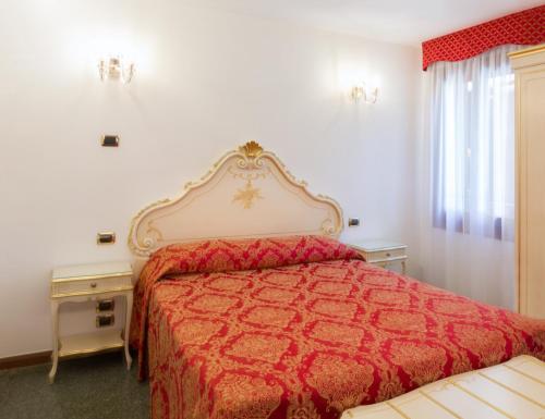 威尼斯莱奥纳多酒店的一间卧室配有一张红色床罩的床