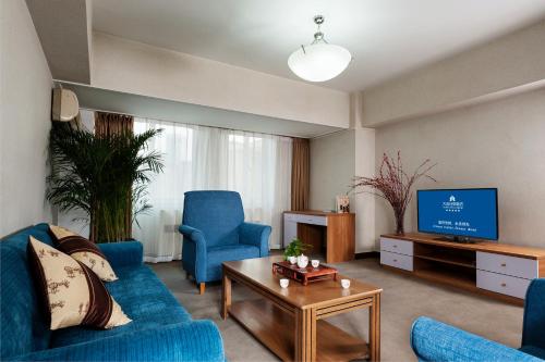 大连大连日航饭店公寓 的客厅配有蓝色的沙发和电视