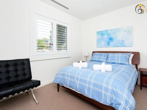 科莱特Luxury in Corlette 4 Drungall Ave的一间卧室配有蓝色的床和一张黑椅