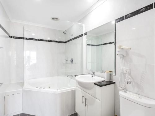 浅滩湾防波堤403号公寓的白色的浴室设有浴缸和水槽。