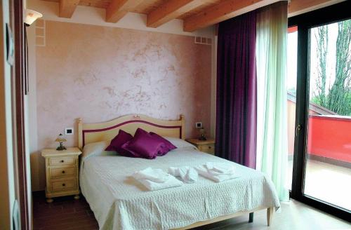 维罗纳自由镇Agriturismo Aver的一间卧室配有一张带紫色枕头的床和窗户。