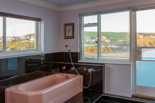 滨海比格伯里Burgh Island Hotel的带窗户的浴室内的粉红色浴缸
