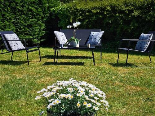 滨海布隆维尔ENTRE TERRE ET MER的草上花草上的三把椅子和一张桌子