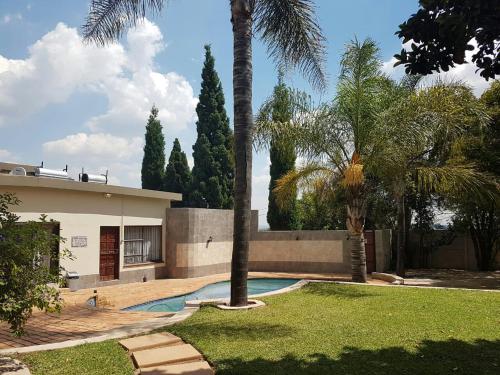 比勒陀利亚Private Apartments & Biz Stays Pretoria的一座带游泳池和棕榈树的房子
