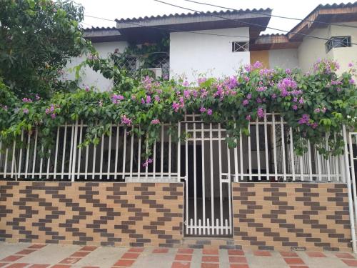 圣玛尔塔Cabaña Midas Rodadero的房屋前方有粉红色花的白色围栏
