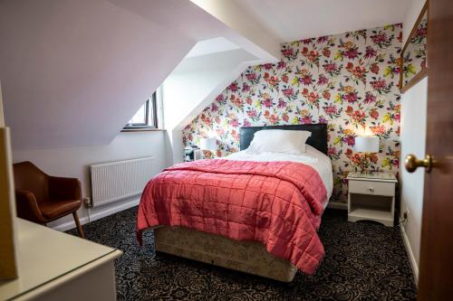 埃文河畔斯特拉特福Quilt and Croissants Guest House的一间卧室配有红色的床和花卉壁纸