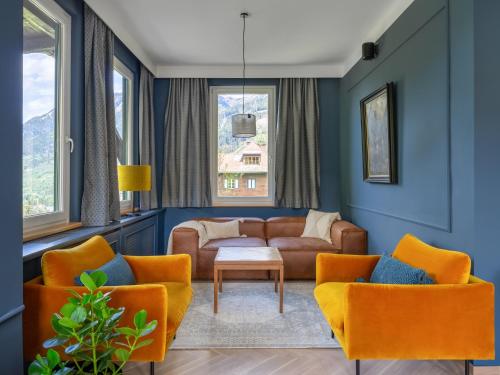 巴德加斯坦Das Schider - Boutique Apart-Hotel的客厅配有橙色椅子和沙发