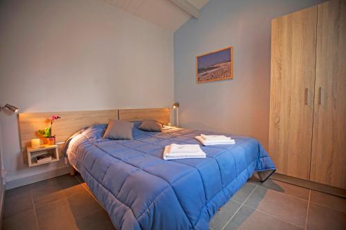 圣特罗让莱班Village Vacances Passion Les Bris的一间卧室配有蓝色的床和毛巾