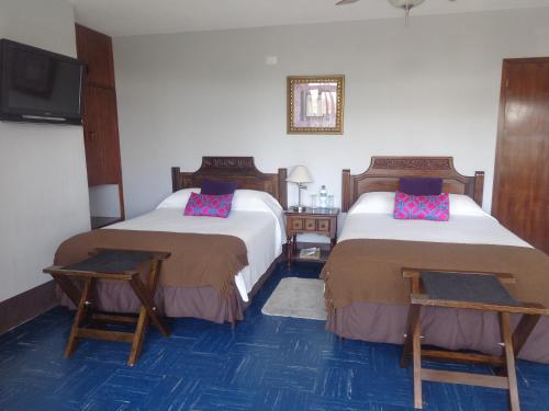 雷塔卢莱乌Hotel Doña Carmen的酒店客房设有两张床和一台平面电视。
