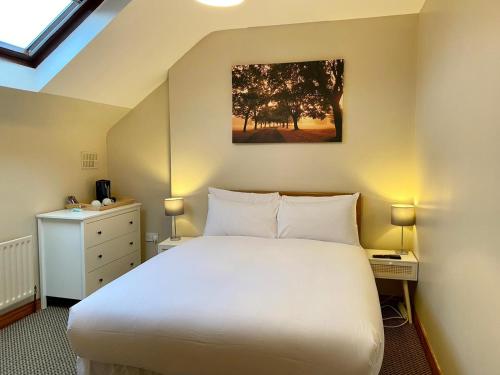 戈尔韦Feeney's Audubon Lodge的卧室配有白色大床和梳妆台