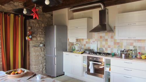 Monte Grimano TermeCasale Le Fontanelle的厨房配有白色橱柜和不锈钢冰箱