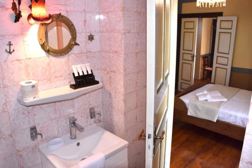 爱琴娜岛Aeginitikon Arhontikon Stylish Boutique Hotel的一间带水槽的浴室和一间带床的房间