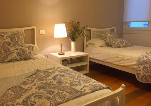 普伦西亚Apartamento Bahía de Plentzia的一间卧室设有两张床和一张桌子上的台灯。