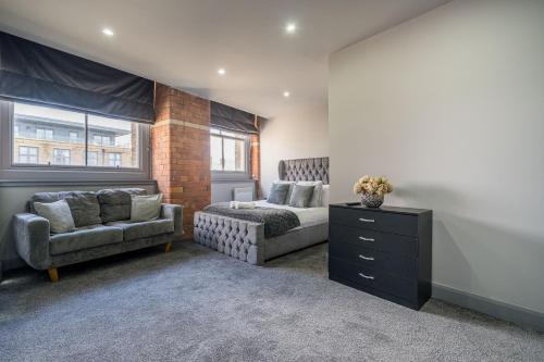 哈德斯菲尔德Hotl Aparts Huddersfield Central的一间卧室配有一张床、一张沙发和一把椅子