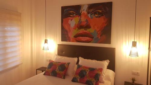 圣波拉Apartamento Pepi Adults Only的卧室配有一张带两个枕头的床上方绘画
