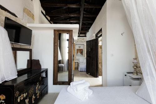 罗希姆诺Antonia's House - Old town的卧室设有白色墙壁和大镜子