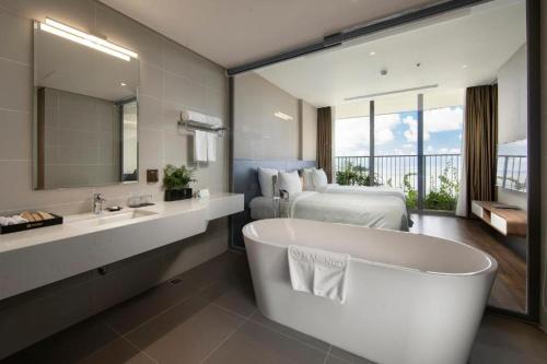 海防Flamingos Cat Ba Resort luxury的一间带大浴缸、一张床和一个浴缸的浴室