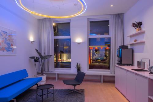 鹿特丹171. Urban Design Hotel的一间带蓝色沙发的客厅和一间厨房