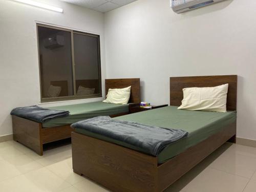 费萨拉巴德• Faizi Furnished Apartments的一间卧室设有两张床和窗户。