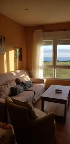 福斯Apartamento en playa de Foz的一间卧室配有一张床、一张沙发和一张桌子