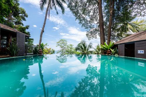 蔻立Baan Krating Khao Lak Resort - SHA plus的棕榈树屋前的游泳池