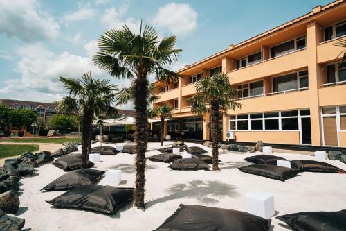 佐洛卡罗斯Belenus Thermalhotel superior的一座庭院,在一座建筑前有棕榈树和睡袋