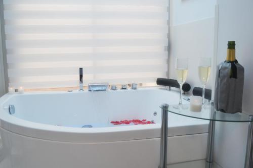 内尔哈Blue Horizon Luxury Apartment的浴缸配有1瓶葡萄酒和2杯葡萄酒