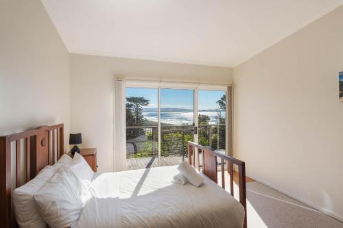 Pambula Beach冲浪道度假屋的一间卧室设有一张床和一个大窗户