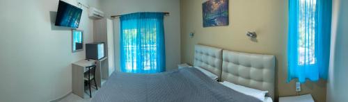 萨莫色雷斯Samothraki Akrogiali Rooms的一间卧室配有一张带蓝色窗帘的床和电视。