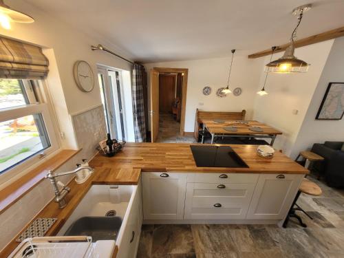 罗厄德南Loch Lomond Blair Byre的厨房以及带水槽和桌子的客厅。