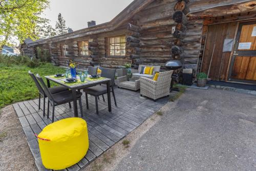 萨利色尔卡Kuukkeli Log Houses Teerenpesä - Superior Suite A49的小木屋前方设有带桌椅的天井。