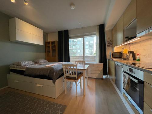 图尔库The Seaside Apartment Turku的一间卧室配有一张床铺和一张桌子,还设有一间厨房