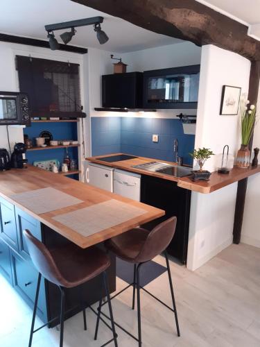 格朗维尔Appartement Haute Ville meublé avec cour privative的厨房配有木桌和蓝色橱柜。