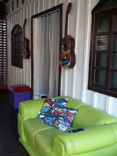 蜜岛RECANTO DO SOL "Aluguel de quartos - Hospedagem Simples"的客厅里配有一张绿色沙发,配有吉他