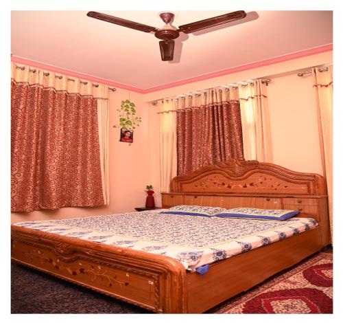 斋浦尔SOHANAs Homestays- 2 BHK Luxury Apartment near Jaipur International Airport的一间卧室配有一张木床和吊扇