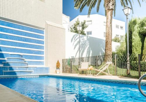 梅里达梅里达旅馆的一座棕榈树游泳池和一座建筑