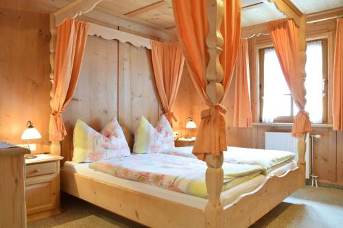 埃尔比格纳尔普Landhaus Huber的一间卧室配有带橙色窗帘的天蓬床